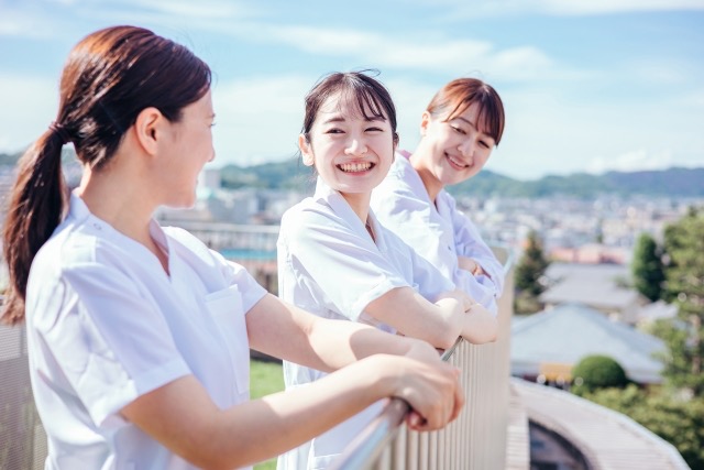 屋上で笑い合う３人の看護師